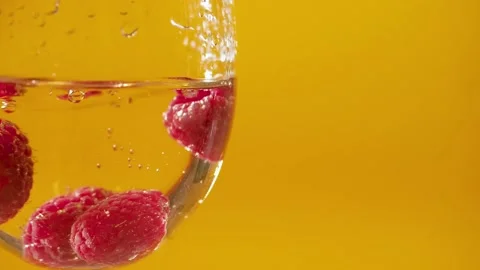 Macro extreme close up. Raspberry falls into glass of white wine alcohol over Stock Footage 149694794