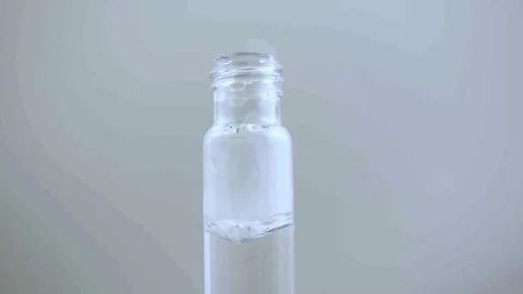 Macro eye dropper create small plum of smoke in vial on white BG Stock Footage 70705326