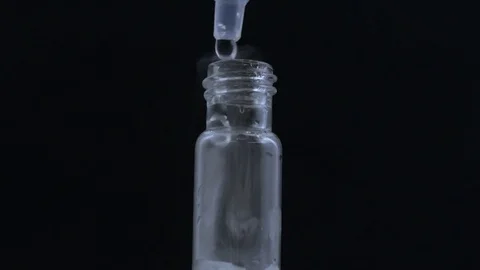 Macro eye dropper creates bubbling smokey vial on black BG Stock Footage 70705818