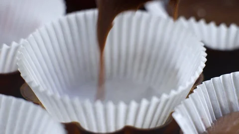 Macro of filling cupcake forms with chocolate dough Stock Footage 128913947