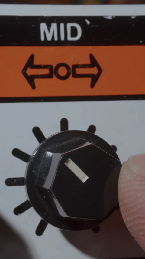 Macro of Finger Adjusting Mid Knob on Vintage Guitar Amplifier Stock-Footage 342454222