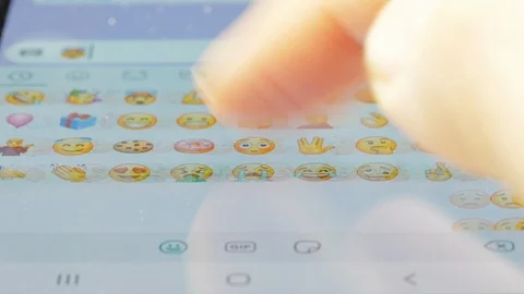 Macro finger browsing emojis on a virtual keyboard Stock Footage 129081011