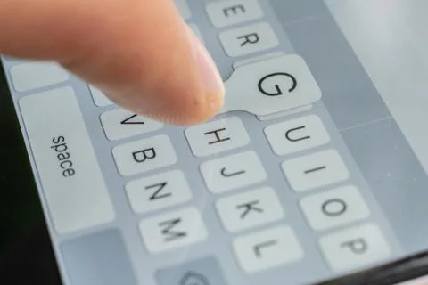 A macro of a finger typing text on the touch screen keyboard of mobile device Stock Photos
