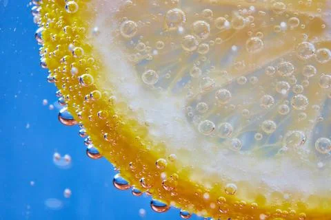 Macro of fizzy bubbles on lemon slice against blue background Foto stock