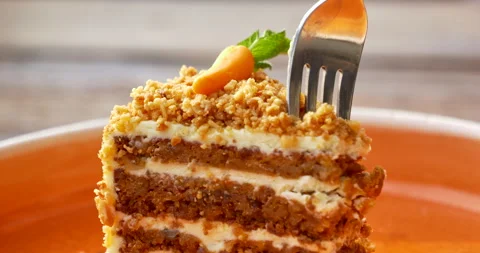Macro fork slicing moist carrot cake topped with nuts and mini carrot Stock-Footage 342936952