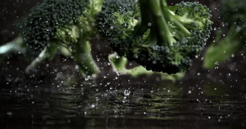 Macro of fresh broccoli cabbage bunches fall with water drops on wooden table Stock Footage 268990068