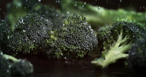 Macro of fresh broccoli cabbage bunches fall with water drops on wooden table Stock Footage 268992092