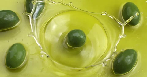 Macro of fresh green olive falling in bio gold liquid extra virgin olive oil Stock Footage 268803392