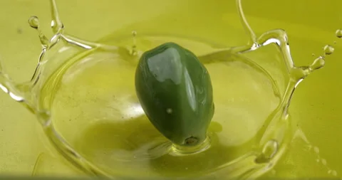 Macro of fresh green olive falling in bio gold liquid extra virgin olive oil Stock Footage 268803505