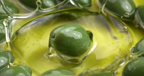 Macro of fresh green olive falling in bio gold liquid extra virgin olive oil Stock Footage 268803530