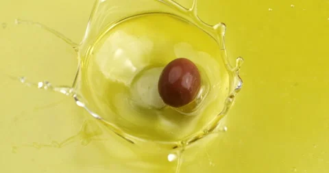 Macro of fresh green olive falling in bio gold liquid extra virgin olive oil Stock Footage 268803535