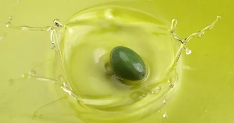 Macro of fresh green olive falling in bio gold liquid extra virgin olive oil Stock Footage 268803553