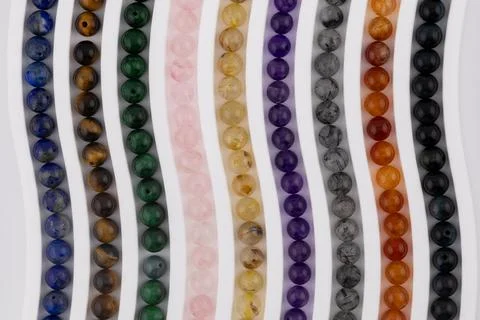 Macro gemstone bead strands arranged in curved pattern on white background Stock Photos