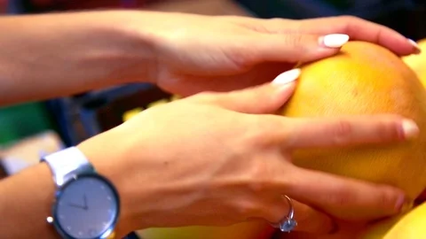 Macro girl hand with ring chooses ripe orange Stock Footage 100342929