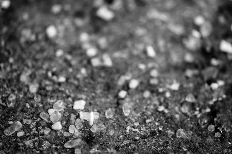 Macro ground level closeup view of rock salt ice-melt on concrete with a frozen Foto stock