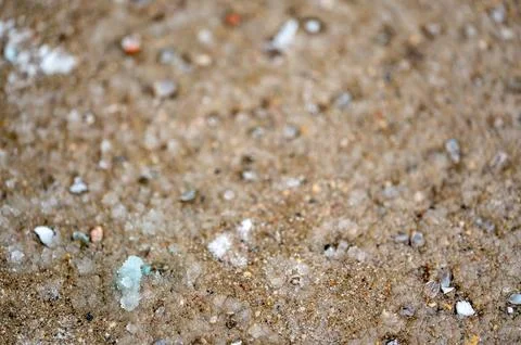 Macro ground level closeup view of rock salt ice-melt on concrete with a frozen Foto stock