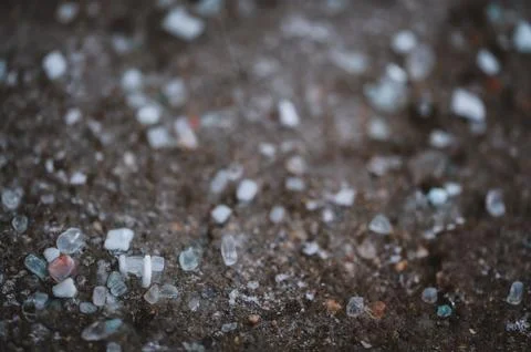 Macro ground level closeup view of rock salt ice-melt on concrete with a frozen Stock Photos