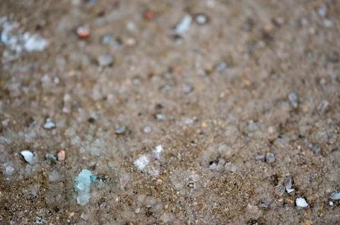 Macro ground level closeup view of rock salt ice-melt on concrete with a frozen Foto stock