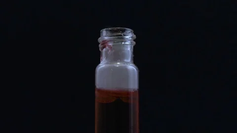 Macro hand picks up bubbling vial of red liquid Stock Footage 70705749