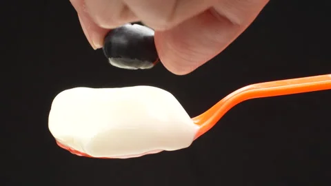 Macro Hand Placing Blueberry on Spoon of Yogurt Isolated Black Background 4K Stock Footage 320656754