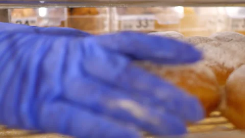 Macro hands in blue gloves take donuts away from stack Stock Footage 102481162