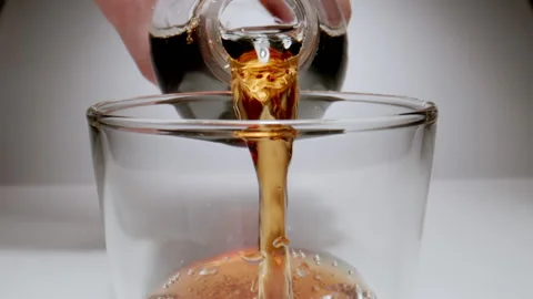 MACRO: Human hand pouring brown beverage from a plastic bottle, slow motion Stock Footage 145825741