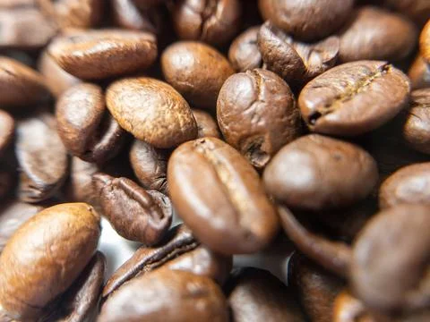 A macro image of coffee beans piled together, showcasing their texture and na Фото