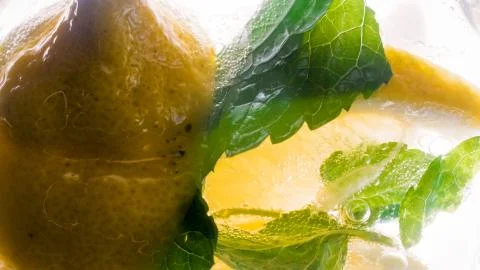 Macro image of lemons and mint leaves in carbonated water Stock Photos