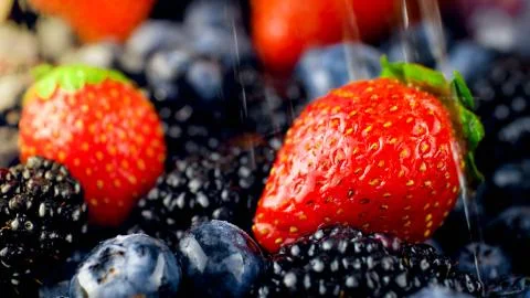 Macro image of water dropelts falling on fresh strawberries, blueberries and Foto stock