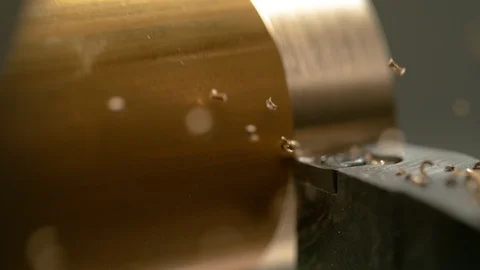 MACRO: Lathing equipment carving the outer layer of a shiny brass workpiece. Video stock 114071739