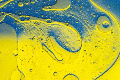 Macro liquid texture with blue and yellow oil drops Stock Photos