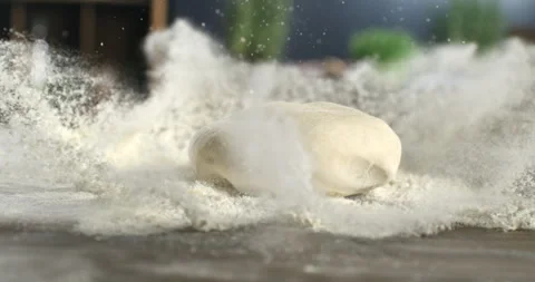 Macro of loaf dough falling with flour splash while baker makes bread or pizza Stock Footage 268834909