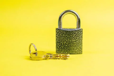 Macro of a locked padlock with the key on yallow background Stock Photos