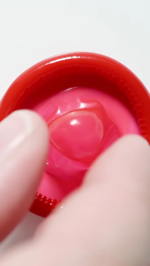 MACRO: Male hand puts a red condom on a white table - Top view Stock Footage 344859073