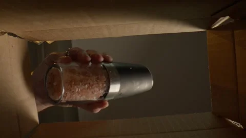 Macro of Man Pulling the salt shaker out of the box from underneath Stock Footage 307577154