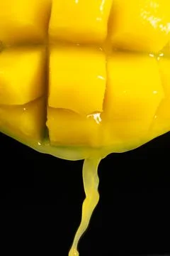Macro of mango juice dripping from sliced fruit cubes Stock Photos
