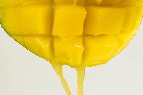 Macro of mango juice dripping from sliced fruit cubes Stock Photos
