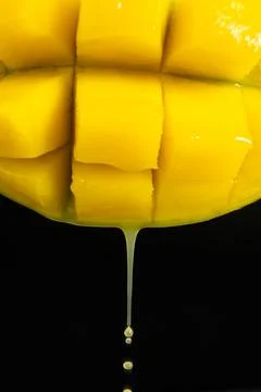 Macro of mango juice dripping from sliced fruit cubes Stock Photos
