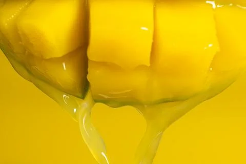 Macro of mango juice dripping from sliced fruit cubes Stock Photos