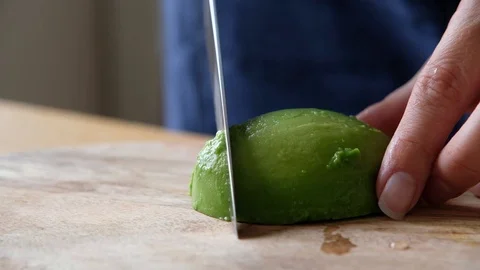 Macro of a middle aged chef cutting avocado with knife on wooden board (extra Stock Footage 111717350