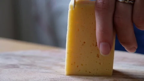Macro of a middle aged chef cutting cheese with knife on wooden board (extra Stock Footage 111717357