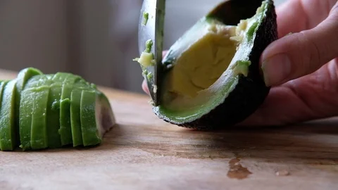 Macro of a middle aged chef pilling avocado with knife on wooden board (extra Stock Footage 111717381