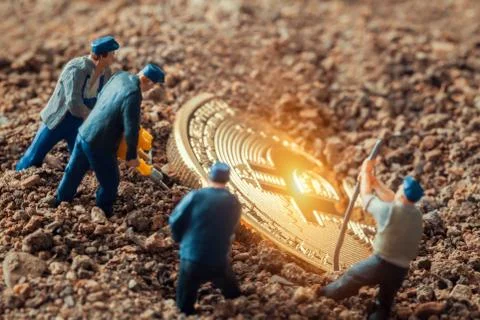 Macro miner figurines digging ground to uncover big shiny bitcoin Stock-Fotos