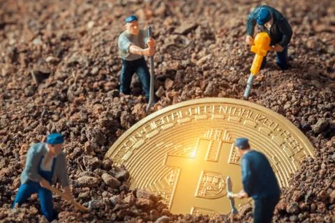 Macro miner figurines digging ground to uncover big shiny bitcoin Stock-Fotos