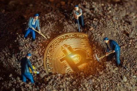 Macro miner figurines digging ground to uncover big shiny bitcoin Stock-Fotos