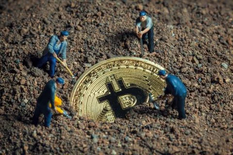 Macro miner figurines digging ground to uncover big shiny bitcoin Stock-Fotos