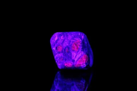 Macro mineral stone ruby under ultraviolet light on a black background Stock Photos