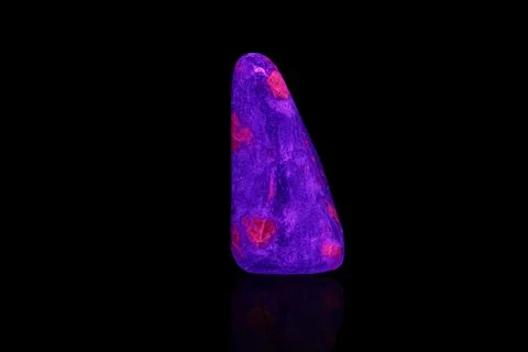 Macro mineral stone ruby under ultraviolet light on a black background Stock Photos