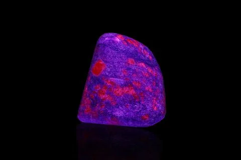 Macro mineral stone ruby under ultraviolet light on a black background 写真素材