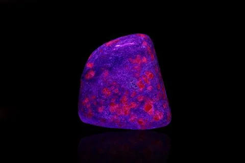 Macro mineral stone ruby under ultraviolet light on a black background 写真素材
